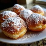 A plate of freshly made Vanilla French Beignets, generously dusted with powdered sugar.
