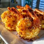 A platter of golden brown Air Fryer Crispy Coconut Shrimp, showcasing the crispy coconut coating and shrimp tails.