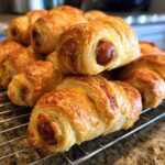 A batch of golden brown Air Fryer Mummy Dogs cooling on a wire rack. Crispy and delicious!