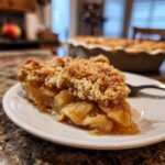 A slice of apple crumble pie, a delicious One-Pan Thanksgiving Desserts option, on a white plate with a fork.