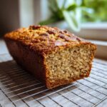 A golden brown loaf of freshly baked banana bread cooling on a wire rack. Perfect for How to Make Banana Bread.