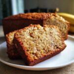 Two slices of delicious homemade Banana Bread in 20 Minutes on a white plate, with the loaf in the background.