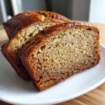Slices of Best Banana Bread 2025, showcasing a crispy crust and juicy interior texture on a white plate.