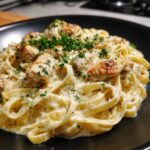Creamy chicken alfredo pasta, a delicious Restaurant-Style Dinner Ideas at Home. Topped with parsley on a black plate.