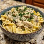 Close-up of a bowl of Creamy Turkey Stroganoff (Lightened) with egg noodles, mushrooms, and parsley garnish.