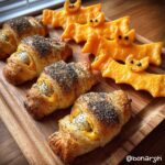 Savory Halloween treats: Egg “Mummies” in croissants and Cheesy Bats on a wooden board.