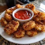 A plate of crispy Ghost Mozzarella Bites with a bowl of marinara sauce for dipping.