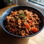 A bowl of savory ground beef recipe with tomatoes and herbs, ready to eat.