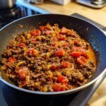Ground beef recipe with diced tomatoes and yellow bell peppers cooking in a skillet. Ultimate Ground Beef Recipes Guide.