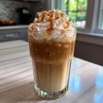 Tall glass of iced Restaurant-Style Starbucks Drinks at Home, topped with whipped cream, caramel drizzle, and sprinkles.