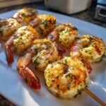Close-up of Lemon Herb Grilled Shrimp Skewers on a white plate, showcasing the herbs and grill marks.