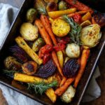 Overhead shot of a colorful One-Pan Thanksgiving Veggie Tray with roasted carrots, beets, Brussels sprouts, and herbs.