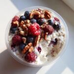 Overhead shot of overnight oats topped with fresh raspberries, blueberries, and pecans, a perfect breakfast ideas.