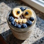 Overnight Oats with Spooky Toppings: banana slices, blueberries, and chocolate chips arranged to resemble a spooky face.