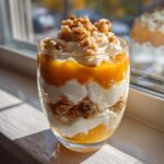 Close-up of a layered Pumpkin Yogurt Parfait (2025) in a glass with granola and yogurt.