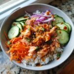 Overhead shot of a colorful Salmon Bowl with rice, salmon, carrots, cucumber, and red onion.