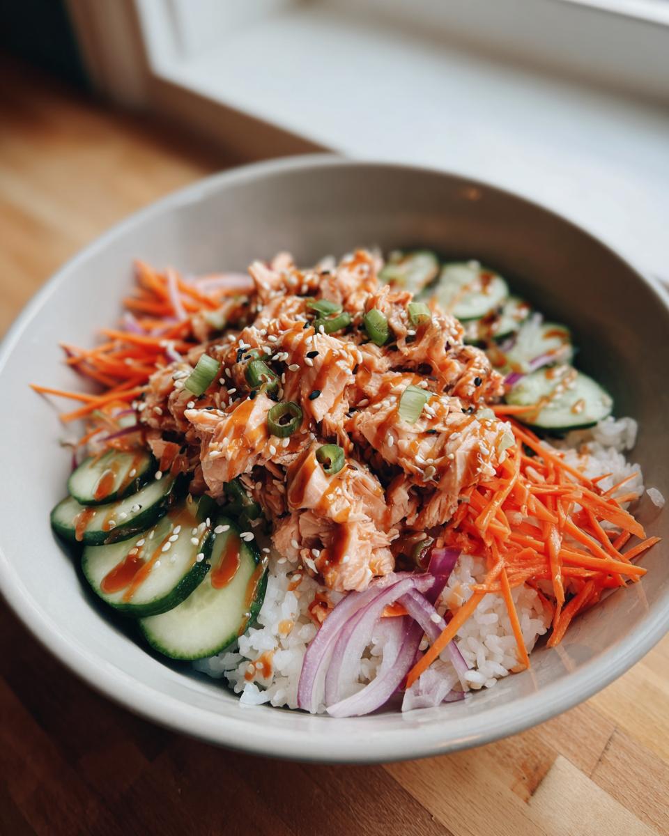 Overhead shot of a Salmon Bowls with rice, salmon, carrots, cucumber, and red onion.