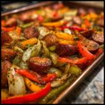 A sheet pan filled with sausage, onions, and bell peppers, showcasing One-Pan Dinner Recipes.