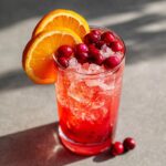 A Restaurant-Style Thanksgiving Drink with cranberries, orange slices, and ice in a glass.