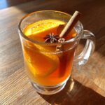 A glass mug filled with Thanksgiving Drinks for Busy Weeknights, garnished with orange slices, cinnamon stick, and star anise.
