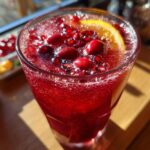 Festive Thanksgiving drinks: a cranberry pomegranate sparkler with an orange slice garnish.