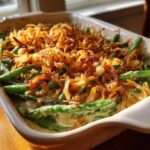 Close up of Thanksgiving Green Beans casserole topped with crispy fried onions in a baking dish.