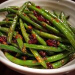 Close-up of Thanksgiving Green Beans with dried cranberries in a white bowl.