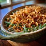 Close-up of Thanksgiving Green Beans Recipe topped with crispy fried onions in a green casserole dish.