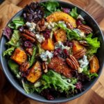 Overhead view of a Thanksgiving Salad recipe with butternut squash, pecans, cranberries, and blue cheese.