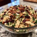 A vibrant Thanksgiving Salad Recipe with quinoa, chicken, cranberries, pecans, and kale in a glass bowl.