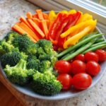 A vibrant Thanksgiving Veggie Tray featuring broccoli, carrots, bell peppers, snap peas, and cherry tomatoes.