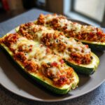 Three Turkey & Quinoa Stuffed Zucchini Boats on a plate, topped with melted cheese.