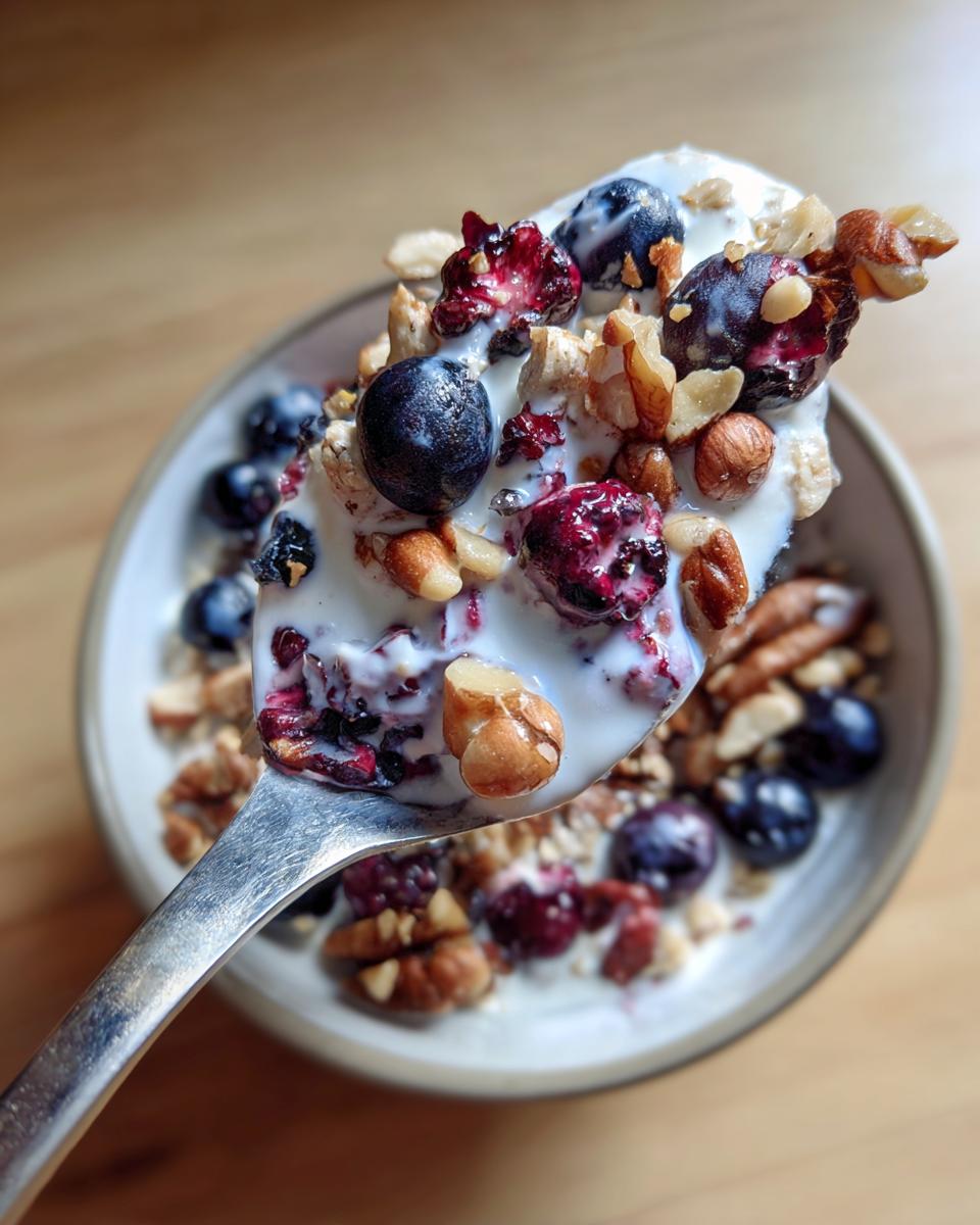 Spoonful of yogurt with blueberries, cranberries, and nuts, illustrating What Makes Perfect Breakfast Ideas? Try This.