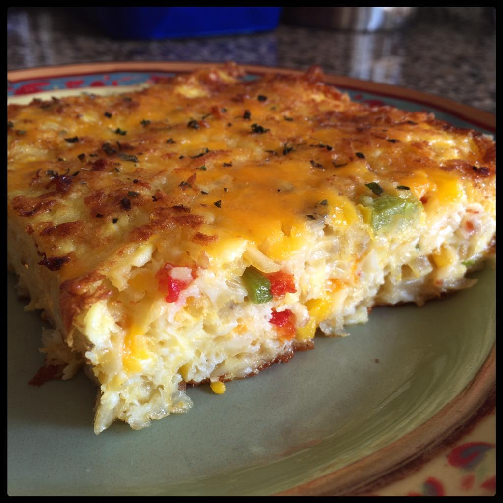 A delicious slice of Cheesy Hashbrown Breakfast Casserole with melted cheese and visible vegetables.