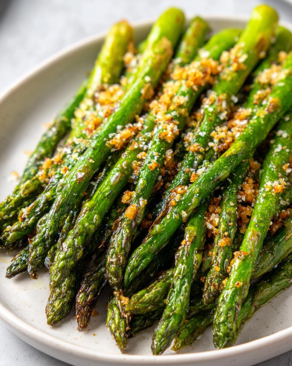 Close-up of perfectly Roasted Asparagus with Parmesan, showing tender green stalks topped with golden breadcrumbs and cheese.