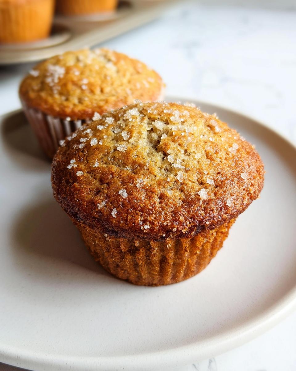 Close-up of a bakery style Banana Muffins, golden brown and topped with coarse sparkling sugar.