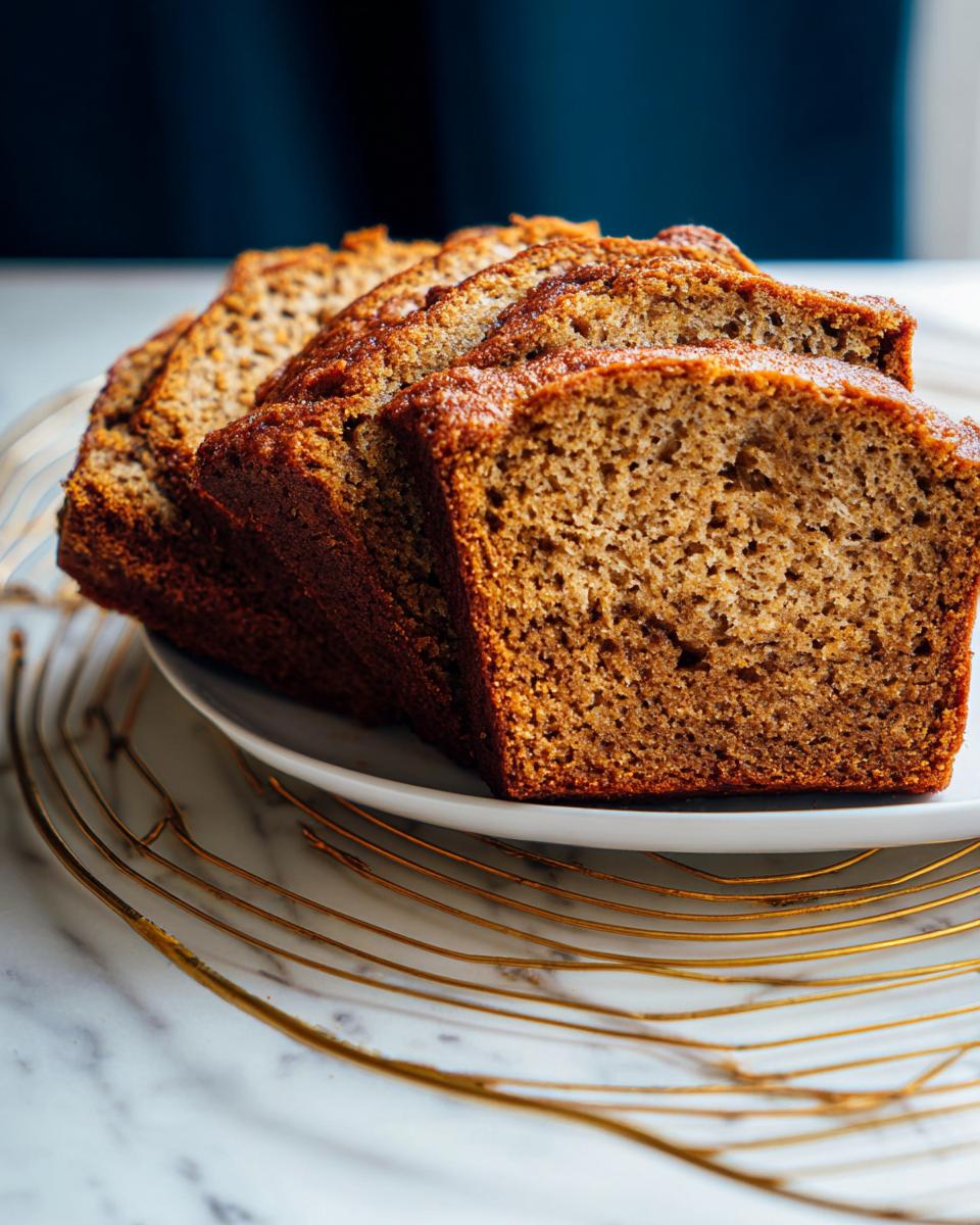 Close-up of several moist slices of Healthy Banana Bread (Whole Wheat) stacked on a white plate.