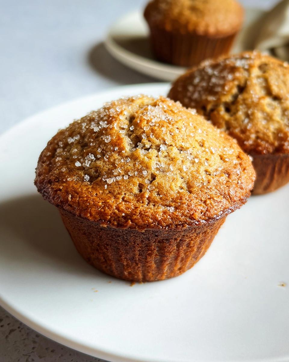 Close-up of a perfectly domed Bakery Style Banana Muffin topped with coarse sugar crystals.