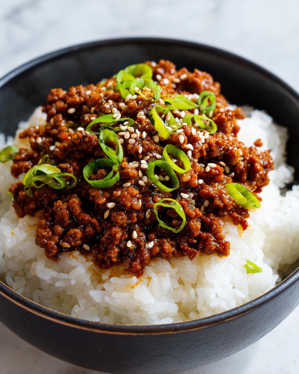Close-up of Quick & Easy Korean Ground Beef Bowl served over white rice, topped with green onions and sesame seeds.