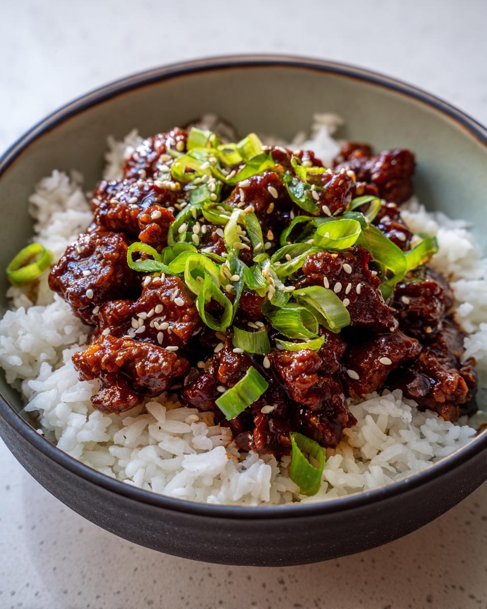 Close-up of a Quick & Easy Korean Ground Beef Bowl served over white rice, topped with green onions and sesame seeds.