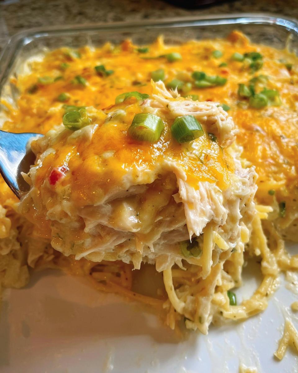A spoonful of cheesy, creamy chicken and pasta casserole topped with melted cheddar and green onions, perfect for Healthy Family Dinners.
