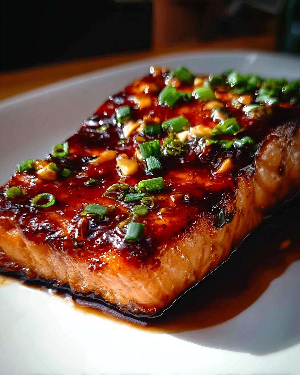 Close-up of a perfectly cooked Honey Soy Glazed Salmon with a sticky finish, topped with chopped green onions.