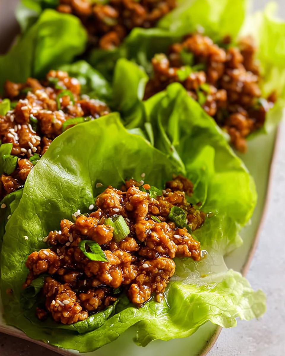Close-up of several Turkey Lettuce Wraps filled with savory ground turkey mixture and garnished with sesame seeds.